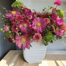 Pink and magenta flowers arranged in a white vase