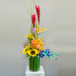 Tall tropical bouquet with sunflowers and orchids in a glass vase