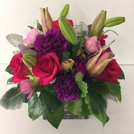 Bouquet of pink and purple flowers with red roses in a glass vase
