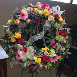Large floral wreath on an easel with multicolored roses and ribbons