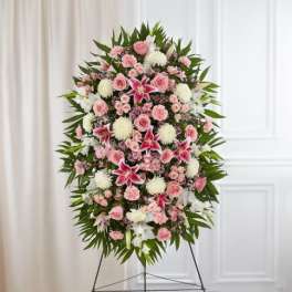 Tall pink and white standing floral spray with lilies, roses, and mums on a metal easel