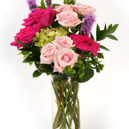 Arrangement of hot pink and light pink roses with green blooms in a clear glass cylinder vase