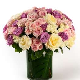 Large dome of pastel roses in a leaf-lined glass cylinder vase