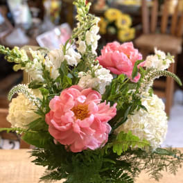 Pink peonies and white flowers arranged in a glass vase