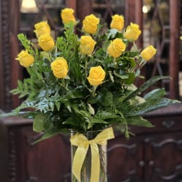 Yellow roses in a clear glass vase with a yellow ribbon