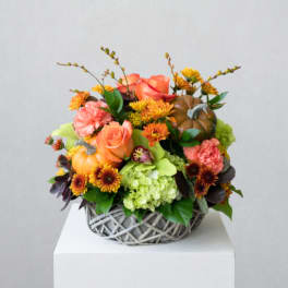 Autumn floral arrangement in a woven basket with pumpkins