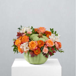Orange and white flowers arranged in a green pumpkin-shaped vase