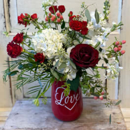 Red roses and white hydrangeas in a red vase with "Love" text.