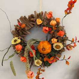 Autumn wreath with orange flowers, dried grasses, and a small pumpkin