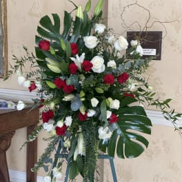 Standing floral spray with red and white roses and lilies on an easel