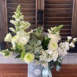 White floral arrangement in a silver tin with a blue ribbon