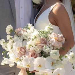 Bride holding a white and blush wedding bouquet with orchids and roses