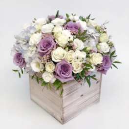 Lavender and white roses arranged in a wooden box