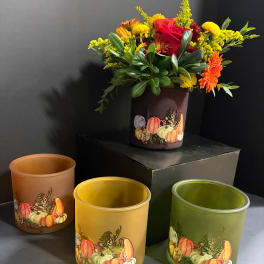 Fall floral arrangement in a pumpkin-decorated vase with yellow, orange, and red blooms