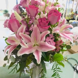 Pink roses and lilies arranged in a clear glass vase