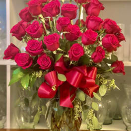 Bouquet of red roses in a glass vase with a red ribbon