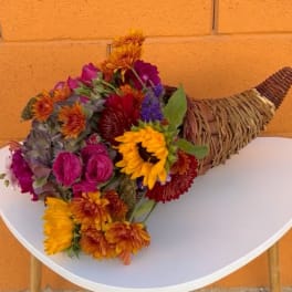 Mixed bouquet with sunflowers, roses, and chrysanthemums in a woven cone wrap