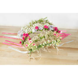 Floral wreaths with pink and white roses on a wooden surface