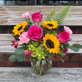Bouquet of pink roses and sunflowers in a glass vase