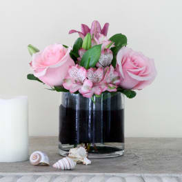 Pink roses and lilies arranged in a clear glass vase