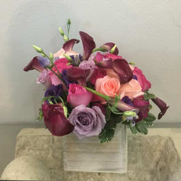 Bouquet of roses and calla lilies in pink, purple, and burgundy tones