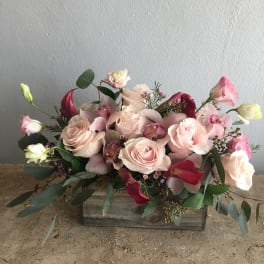 Pink roses and calla lilies arranged in a wooden box