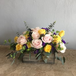 Arrangement of pink and yellow roses in a wooden box