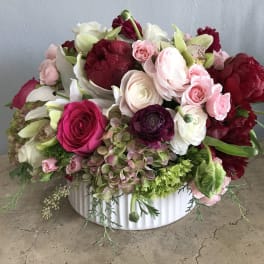 Mixed pink, white, and burgundy flowers in a white bowl vase