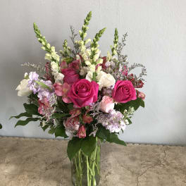 Bouquet of pink roses, snapdragons, and mixed blooms in a clear glass vase