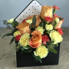 Orange roses and yellow carnations in a black gift box