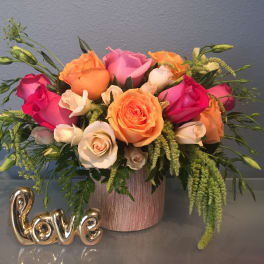 Mixed rose bouquet in a pink vase with a gold "love" decoration