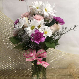 Bouquet of white daisies, pink carnations, and pale roses in a glass vase