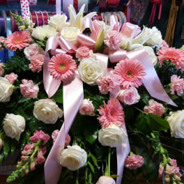Pink and white floral casket spray with ribbon accents