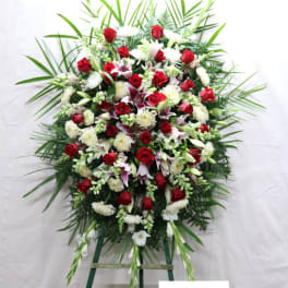 Large standing floral spray with red and white flowers on a green easel