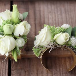 White rose wrist corsage with green accents on a band