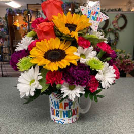 Birthday bouquet with sunflowers, roses, daisies, and carnations in a mug