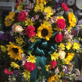 Large wreath with sunflowers, carnations, and a teal ribbon bow