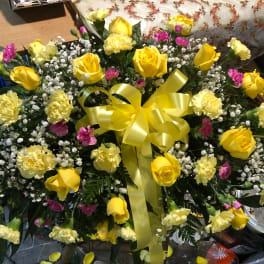 Yellow roses and carnations arranged with a yellow ribbon bow