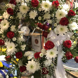 Heart-shaped wreath of red roses and white daisies with a white ribbon