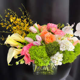 Mixed bouquet in a clear glass vase with pink, peach, white, and yellow flowers