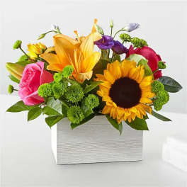 Mixed bouquet with sunflowers, lilies, roses, and a white box container