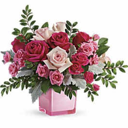 Pink and white roses arranged in a pink glass vase