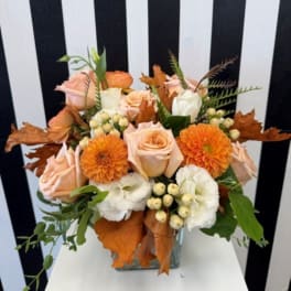 Peach and orange floral arrangement in a clear glass vase