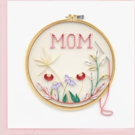 Quilled paper art in an embroidery hoop spelling MOM with floral designs