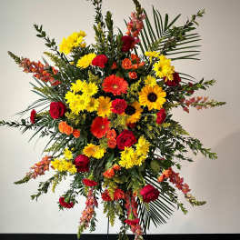 Tall standing floral spray with red, yellow, and orange blooms