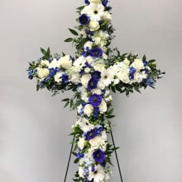 Standing floral cross of white and blue flowers on a metal easel