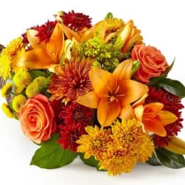 Orange and red mixed bouquet with roses and lilies in a wicker wrap