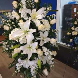 Large white funeral spray with lilies and roses on a stand