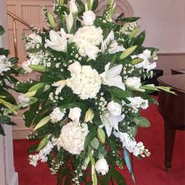 Large white floral standing spray with lilies and roses on an easel