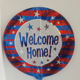 Round foil balloon with "Welcome Home!" text in red, white, and blue